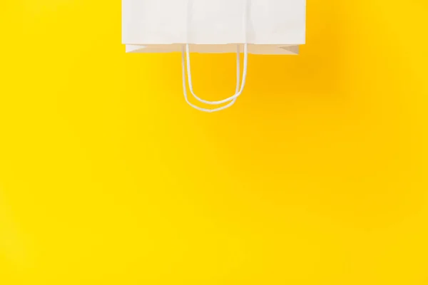 Blank white paper bag isolated on yellow background. Black friday, sale, discount, recycling, shopping and ecology concept