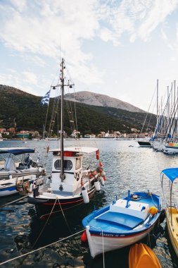 Agia Efimia, Cephalonia island, Greece - July, 12 2019: Small fishing boats and white yachts anchored in a bay of Cephalonia island, Greece