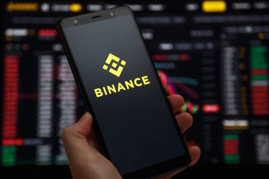 Ukraine, Odessa - June, 1 2021: Binance mobile app running at smartphone screen with a trading page at background. Binance one of the world's leading cryptocurrency exchange and trading platform.