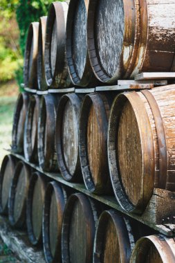 Close up of wooden old wine barrels stacked outside of a winery on vineyard.
