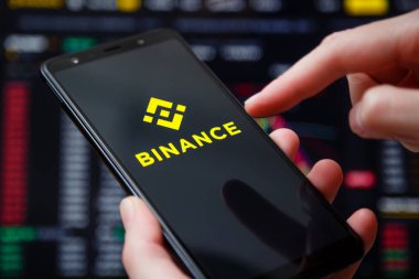 Ukraine, Odessa - June, 1 2021: Binance mobile app running at smartphone screen with a trading page at background. Binance one of the world's leading cryptocurrency exchange and trading platform.