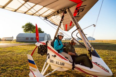 Odessa, Ukraine - July 14, 2016: Young smiling woman with pilot preparing to start the flight at motor hang glider