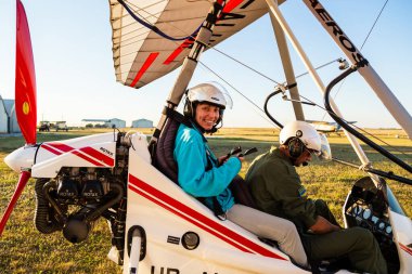 Odessa, Ukraine - July 14, 2016: Young happy girl with pilot preparing to start the flight at motor hang glider