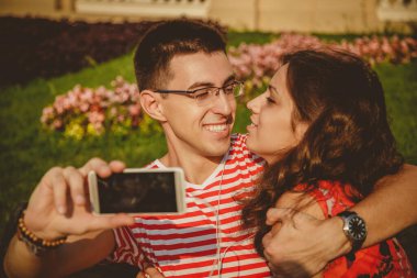Happy beautiful couple taking selfie on mobile phone, hugging and having fun together.