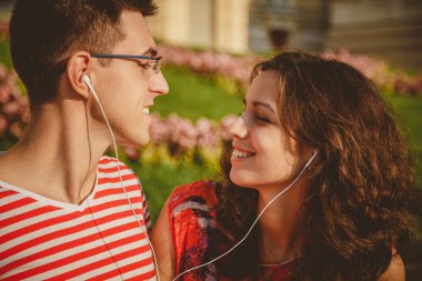 Close up of happy young couple having fun at park while listening to music.