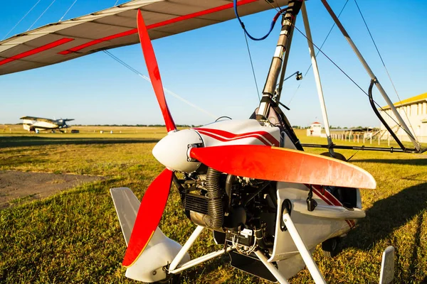 Close up of propellerof motor hang glider standing on green grass at aerodrome, bright summer day.