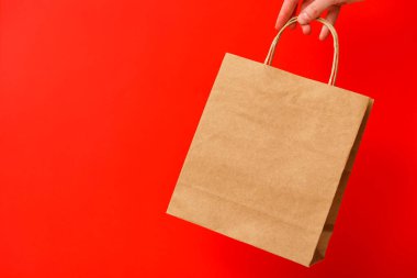 Kırmızı arka planda izole edilmiş kahverengi el çantasıyla gezen kadın. Kara Cuma indirimi, geri dönüşüm, alışveriş ve ekoloji konsepti