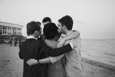 ODESSA, UKRAINE - MAY 30, 2015: Young people hugging in circle standing together outside at the beach graduation party.
