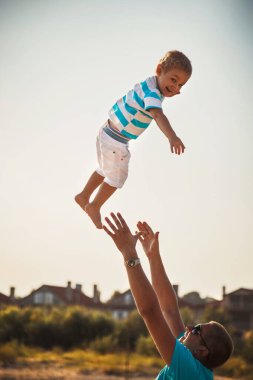 Happy father and son playing together at beach. Father throwing his son in the air.