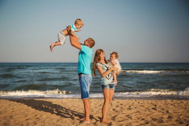 Young happy loving family with small kids having fun at beach together near the ocean, happy lifestyle family concept.