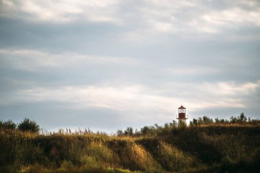 Deniz kıyısındaki eski beyaz deniz feneri, yaz manzarası.