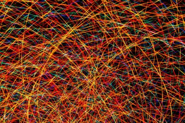 Renkli ışık, siyah arkaplanda kırmızı, yeşil, mavi ve sarı çizgilerle soyut uzun pozlama görüntüsü çiziyor.
