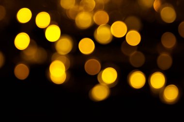 Abstract gold bokeh on black background. Defocused yellow lights, abstract texture.