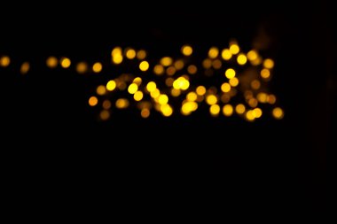 Abstract gold bokeh on black background. Defocused yellow lights, abstract texture.