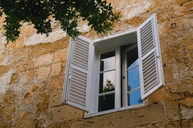 Typical traditional window with white wooden blind at narrow medieval street in Mdina, ancient capital of Malta, fortified medieval town. Popular touristic destination and attraction.