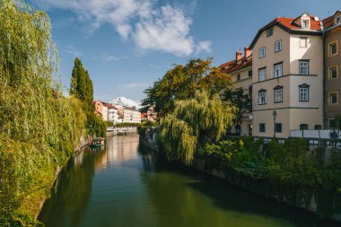 Ljubljana, Slovenia - September, 8 2018: Beautiful view at river Ljubljanica, tourist centre of Ljubljana, capital of Slovenia. With small excursion boats and people relaxing in cafes.