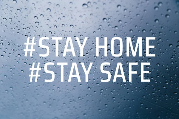 Stay home stay safe concept. Stay at home social media campaign for coronavirus COVID-19 prevention. Close up of rain drops on the window at background.
