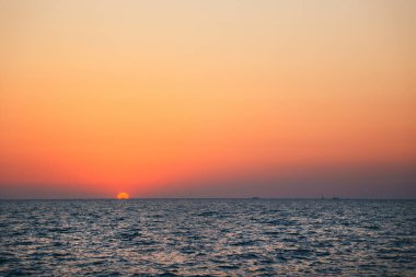 Turuncu mavi bir gün doğumu gökyüzü, deniz suyunun üstünde bir şafak, günbatımı arka planı.