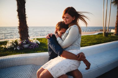 Şirin, genç ve güzel bir çift deniz kenarında oturup birbirlerine sarılıyorlar..