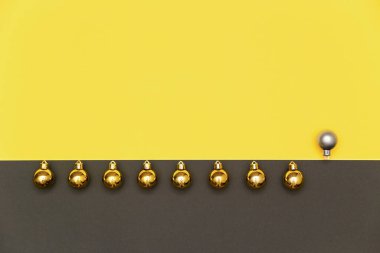 Christmas background in colors of the 2021 year Illuminating and gray. Christmas gold balls and one gray in a line on yellow and gray background