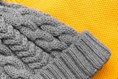 Close up of knitted yellow sweater and gray hat on it in trendy colors. Colors of the 2021 year. Cozy knitted clothing, warm concept.