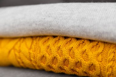 Knitted pullovers close up in trendy grey and yellow colors. Colors of the 2021 year. Stack of cozy knitted sweaters, winter concept.