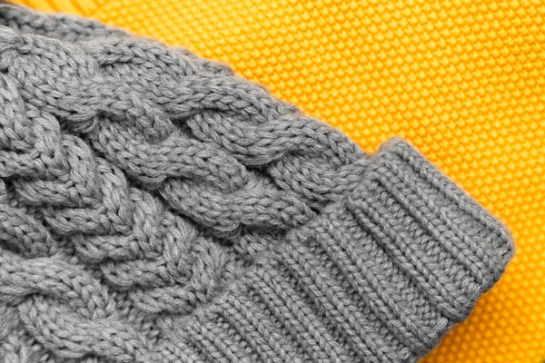 Close up of knitted yellow sweater and gray hat on it in trendy colors. Colors of the 2021 year. Cozy knitted clothing, warm concept.