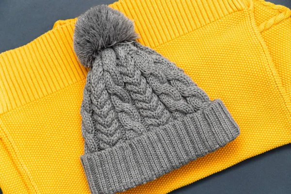 Knitted yellow sweater and knitted gray hat on it in trendy colors on a grey background. Colors of the 2021 year. Cozy knitted clothing, warm concept.