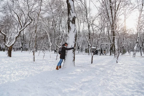 Young Woman Embracing Big Tree Her Eyes Closed Snow Covered — Stock fotografie