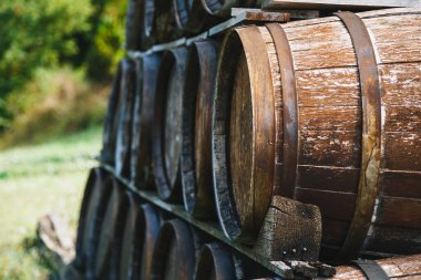 Close up of wooden old wine barrels stacked outside of a winery on vineyard.