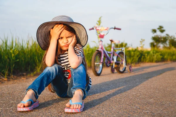 Cute Little Unhappy Girl Big Sun Hat Sitting Road Her — Stockfoto