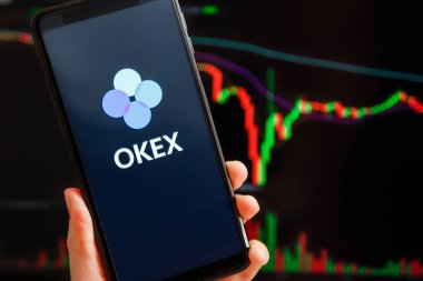 Ukraine, Odessa - September, 7 2021: OKEx mobile app running at smartphone screen with trading candlestick chart at background. OKEx is cryptocurrency exchange and trading platform