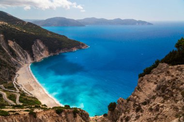 Myrtos Sahili 'nin üst manzarası ve muhteşem turkuaz ve mavi İyon Denizi suyu. Gökyüzü manzarası, ünlü ve son derece popüler Cephalonia, Yunanistan ve Avrupa 'daki yaz manzarası