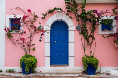 Asos köyünde renkli mavi kapılı ve pembe duvarlı geleneksel Yunan evi. Assos yarımadasının ünlü ve son derece popüler seyahat merkezi Cephalonia, Yunanistan ve Avrupa 'da