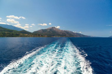 Yaz zamanı bir yolcu gemisinin arkasında açık deniz suyu izi. Feribot, Akdeniz 'in mavi ve berrak sularında Sefalonya Adası, Yunanistan' dan ayrılan bir iz bırakıyor.