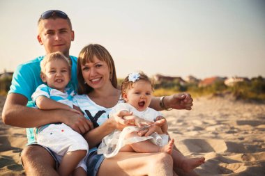 Close up of young happy loving family with small kids in the middle, having fun at beach together near the ocean, happy lifestyle family concept.