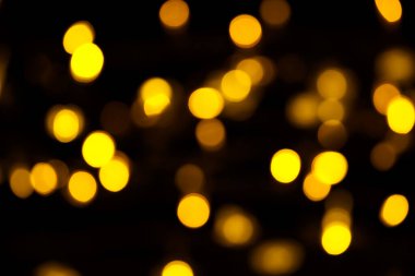 Abstract gold bokeh on black background. Defocused yellow lights, abstract texture.