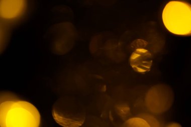Abstract gold bokeh on black background. Defocused yellow lights, abstract texture.