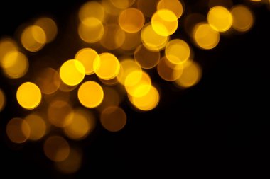 Abstract gold bokeh on black background. Defocused yellow lights, abstract texture.