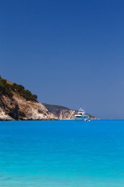 Beyaz yat Myrtos Sahili turkuaz ve mavi körfeze demirlemiş. Sefalonya Adası, Yunanistan ve Avrupa 'daki ünlü ve son derece popüler seyahat merkezinin yaz manzarası