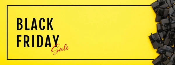 Black Friday banner. Black gift boxes with black ribbons on bright rich yellow background. Black friday sale, discount, shopping concept