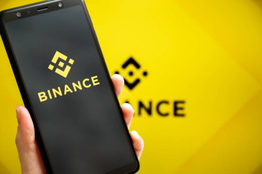 Ukrayna, Odessa - 9 Ekim 2021: Binance mobil uygulaması arkaplanda Binance logosu olan akıllı telefon ekranında çalışıyor. Binance dünyanın önde gelen kripto döviz ve ticaret platformlarından biri.