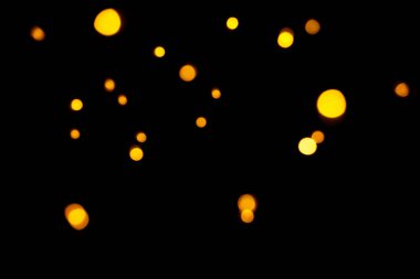 Koyu arkaplanda altın bokeh. Odaklanmamış altın ışıklar. Yeni yıl, Noel arkaplanı, soyut doku