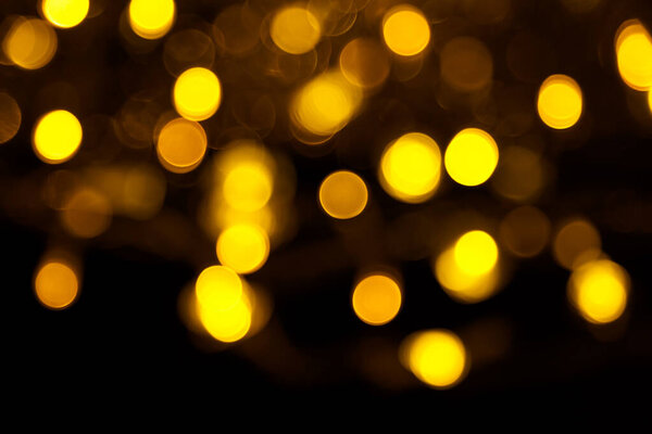 Abstract gold bokeh on black background. Defocused yellow lights, abstract texture.