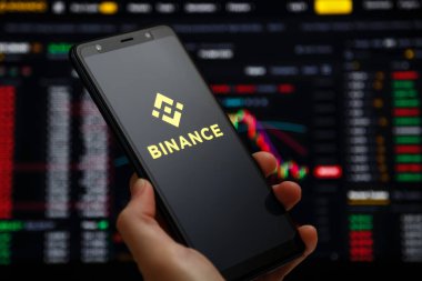 Ukraine, Odessa - June, 1 2021: Binance mobile app running at smartphone screen with a trading page at background. Binance one of the world's leading cryptocurrency exchange and trading platform.