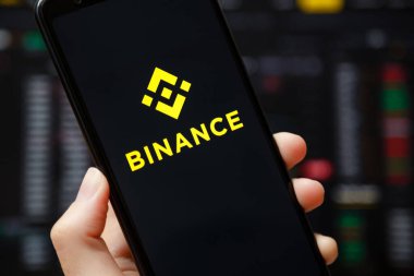 Ukraine, Odessa - June, 1 2021: Binance mobile app running at smartphone screen with a trading page at background. Binance one of the world's leading cryptocurrency exchange and trading platform.