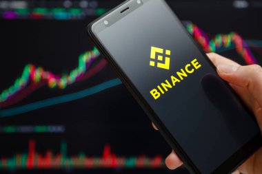 Ukrayna, Odessa - Haziran, 12021: Akıllı telefon ekranında çalışan Binance mobil uygulaması ve arka planda ticari şamdan şeması. Dünyanın önde gelen kripto döviz ve ticaret platformlarından biri..