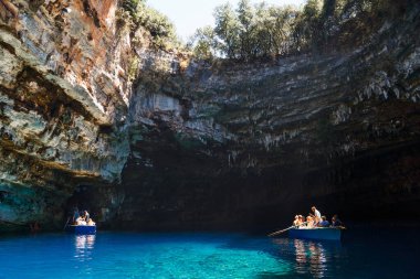Melissani Mağarası, Cephalonia Adası, Yunanistan - 14 Temmuz 2019: Melissani Gölü 'nün ortasında turistli küçük tekneler ve fantastik mavi deniz suyu