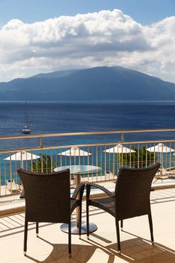 Yaz balkonunda kahve masası, rahat sandalyeler ve muhteşem deniz manzarası. Yunan adalarında sabah. Agia Efimia Körfezi 'nin güzel manzarası bir otel, villa balkonu, Cephalonia adası, Yunanistan.
