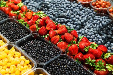 Markette farklı taze meyvelerin renkli karışımı. Ahududu, çilek, yabanmersini ve yabanmersini